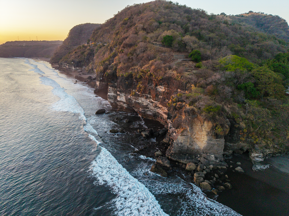 Mirador costero que enmarca la playa de arena y el borde rocoso del acantilado que define el terreno